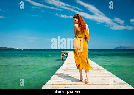 rote kurzhaarige Frau am karibischen tropischen Ozean Pier in sonnigem Wetter blauen Himmel weiße Wolken Freiheit Reisen Urlaub Konzept Stockfoto