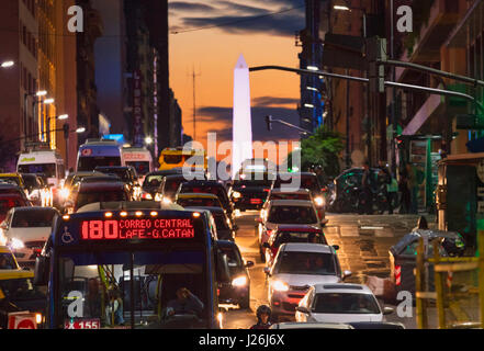 Verkehr auf der Avenida Corrientes in der Dämmerung mit dem Obelisken im Hintergrund. Buenos Aires, Argentinien. Stockfoto