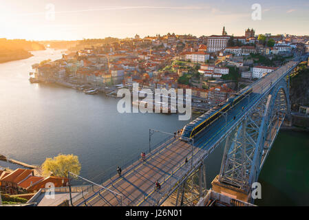 Douro Porto Portugal, Blick bei Sonnenuntergang auf eine U-Bahn, die über die obere Ebene der Ponte Dom Luis I Brücke gegen die Skyline von Porto rast. Stockfoto