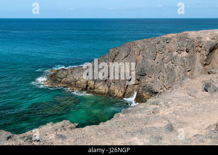 Dunklen Felsen in der Nähe von El Cotillo in Fuerteventura, Spanien mit ruhiger See. Stockfoto