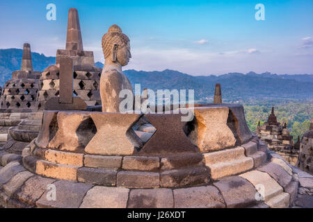 Buddha-Statue und Stupa bei Sonnenaufgang im buddhistischen Tempel von Borobudur. Erbaut im 9. Jahrhundert, UNESCO-Weltkulturerbe. Zentral-Java, Indonesien Stockfoto