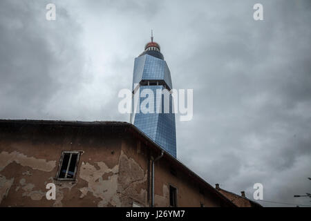 SARAJEVO, Bosnien-Herzegowina - 16. April 2017: Avaz Twist Tower im Regen mit einem zerstörten alten Haus vor. Avaz Turm ist einer der wichtigsten symbol Stockfoto