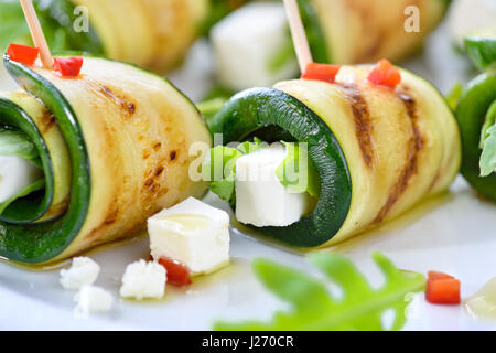 Leckere Brötchen von gebratenen Zucchinischeiben und Feta-Käse mit Rucola, serviert mit Olivenöl und Paprika Stockfoto