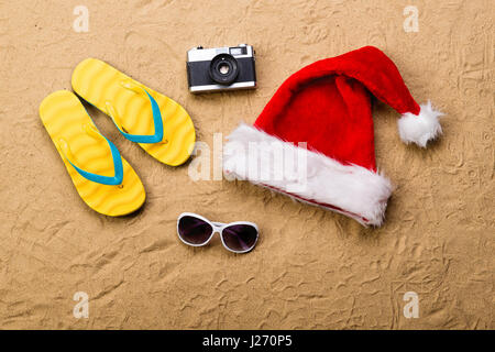 Paar Flip flop Sandalen, Sonnenbrillen, Weihnachtsmütze und Kamera. Stockfoto