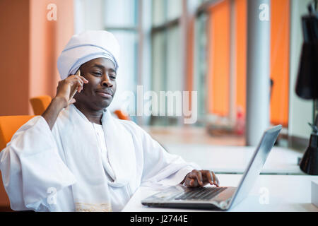 Sudanesische Business-Mann in traditioneller Kleidung mit Handy im Büro Stockfoto