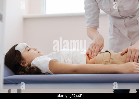 Nette attraktive Kinderarzt auf den Magen drücken Stockfoto