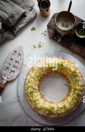 Key Lime Bundt Kuchen glasiert mit Key Lime Glasur und gekrönt mit Limettenschale auf einen Marmortisch in Draufsicht Stockfoto