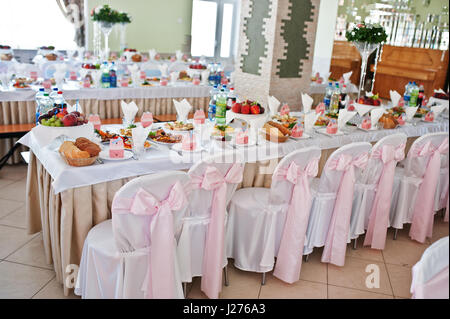 Stühle mit rosa Schleife im Hochzeitssaal. Stockfoto
