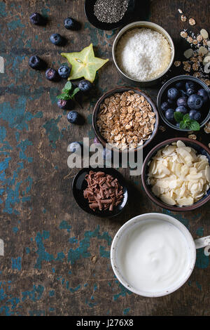 Zutaten für die Herstellung von Smoothies für gesundes Frühstück. Schalen mit Joghurt, Heidelbeeren, Müsli, Mandel Chia-Samen, Kokos, Milch, Schokolade, Minze, caram Stockfoto