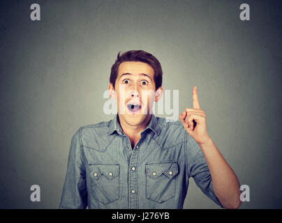 Junger Mann hat Ahnung, zeigen mit dem Finger isoliert auf grauem Hintergrund. Intelligenter Kerl ein Problem gelöst. Positiven Gesichtsausdruck, Körpersprache, Leben perc Stockfoto