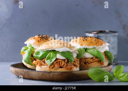 Hausgemachte Mini-Burger mit gezogener Huhn, Basilikum, Mozzarella-Käse und Joghurt-Sauce auf Holzplatte über graue Textur Hintergrund. Gesundes Fast Food c Stockfoto