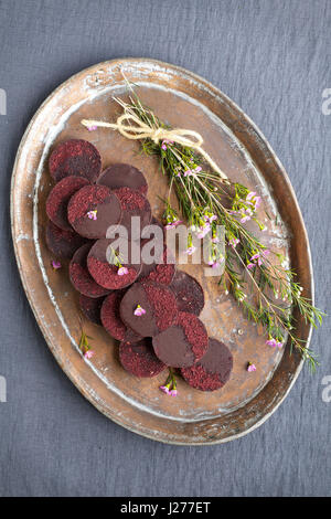 Marzipan-Hibiscus-Tassen serviert auf einem Kupfertablett. Phototgraphed auf eine graue Tischdecke. Stockfoto