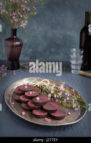 Marzipan-Hibiscus-Tassen serviert auf einem Kupfertablett mit Dessertwein. Phototgraphed auf eine graue Tischdecke. Stockfoto