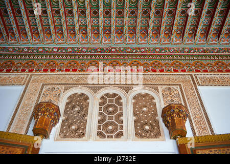 Berber Arabesken bemalte Holzdecke und Morcabe Platerwork Tür umgibt. Die Petite Gericht, Bahia-Palast, Marrakesch, Marokko Stockfoto