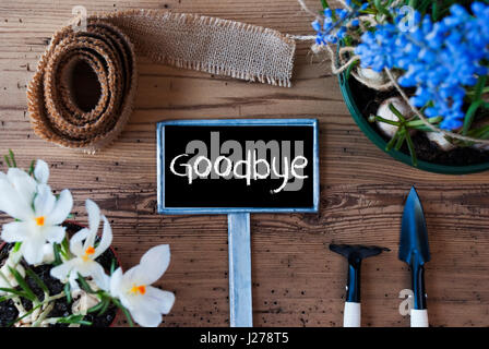 Schild mit englischen Text auf Wiedersehen. Frühlingsblumen wie Trauben Hyazinthe und Krokus. Gartengeräte wie Harke und Schaufel. Hanf-Webband. Im Alter von Holz B Stockfoto