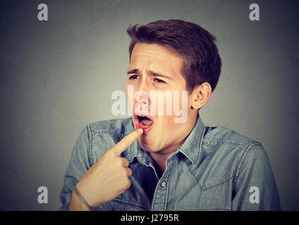 angewidert Mann mit Finger im Mund unzufrieden bereit, Kotzen auf graue Wand Hintergrund isoliert. Menschliche Emotionen Körpersprache Stockfoto