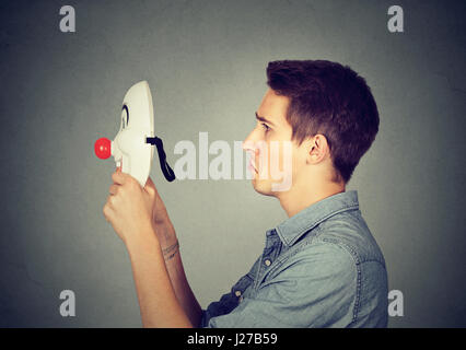 Trauriger Mann glücklich Clownsmaske aufsetzen Stockfoto