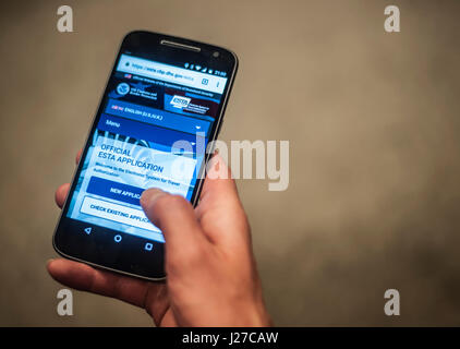 Ein Mann, der über sein Mobiltelefon auf die offizielle Website des US-Heimatschutzministeriums für die Befreiung von der Visumpflicht (Esta) zugreift. Das System verlangt, dass internationale Reisende, die von den Visabestimmungen befreit sind, einen Esta beantragen, der für Electronic System for Travel Authorization steht, und vor der Einreise eine kleine Gebühr - rund &ACIRC;£10 - zahlen. Stockfoto