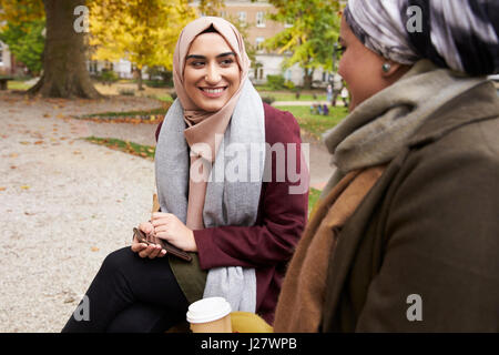 Zwei britische muslimische Frauen beim Mittagessen im Park zusammen Stockfoto