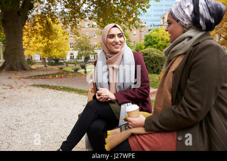 Zwei britische muslimische Frauen beim Mittagessen im Park zusammen Stockfoto