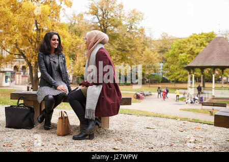 Zwei britische muslimische Frauen treffen im Stadtpark Stockfoto