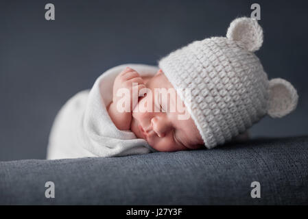 Neugeborenes Baby 2 Wochen alt, schlafen auf weichen blauen flauschige Decke mit funky Wollmütze Stockfoto