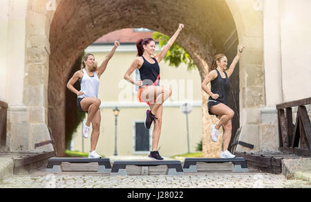 Lächelnde Frauen verstärkt auf Stepper im freien training Stockfoto