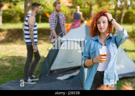 Rothaarige lockiges weiblich halten Glas Bier im Camp in der Natur Stockfoto