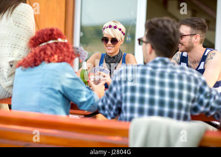 Jungs und Mädels in schönen Frühlingstag im Restaurant im Freien spielen Karten, trinkt Bier und macht Witz Stockfoto