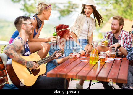 Fröhliche junge Freunde, die zusammen mit Musik und Bier in der Natur genießen Stockfoto