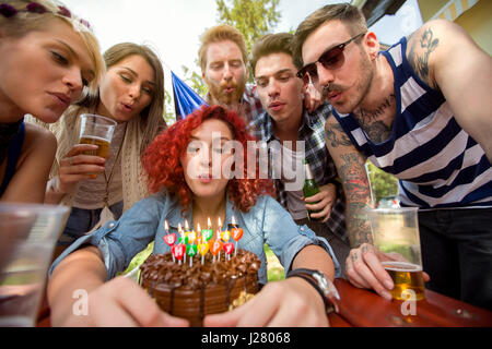 Geburtstag-Mädchen bläst Kerzen auf Schokolade Geburtstagskuchen mit Freunden Stockfoto