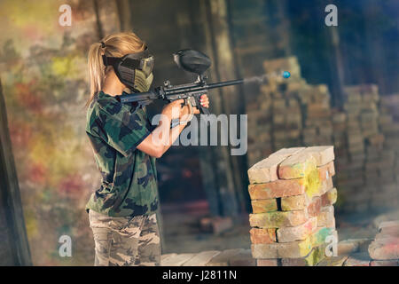 Weibliche Paintball Spieler in Aktion, Shooter auf gegnerische team Stockfoto