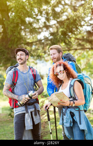 Gruppe von Wanderern im Wald mit Rucksack, Thermoskanne, Karte und Wandern Stöcke im grünen Wald Stockfoto