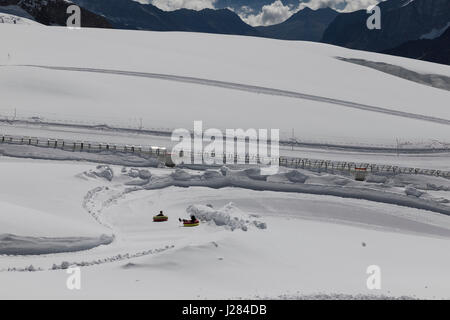 Erhöhte Ansicht der Kinder gleiten auf aufblasbaren Ringen im Schnee bedeckt Feld Stockfoto