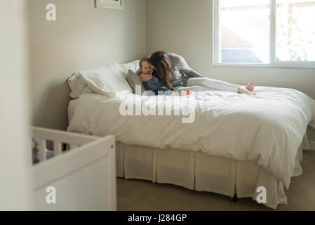 Mutter küssen Sohn beim Sitzen auf dem Bett zu Hause Stockfoto