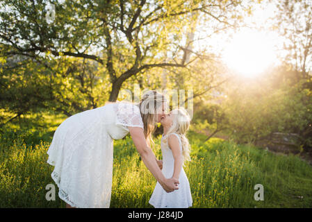 Seitenansicht der schwangeren Mutter küssen Tochter im park Stockfoto