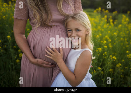 Mittelteil der schwangeren Mutter mit glücklichen Tochter im park Stockfoto