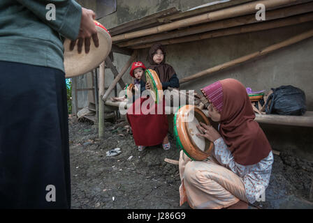 Eine Gruppe von Kindern auf dem Land, die rebana spielen, während sie sich für eine islamische Musikszene in Buni, Bekasi, West Java, Indonesien ausbilden. Stockfoto