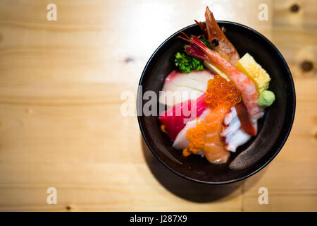 Chirashi Sushi, japanisch essen Reis mit rohem Lachs Sashimi, gemischte Meeresfrüchte, Ansicht von oben, dunkler Rand, kopieren auf Holztisch, auf Lachs Ei Fokus Stockfoto