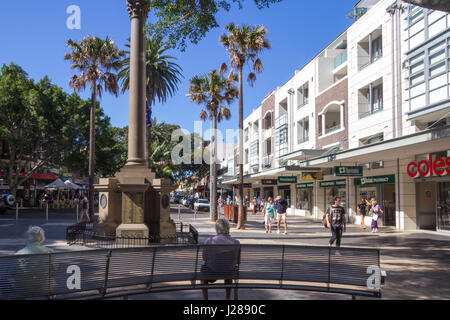 Menschen sitzen auf einer Bank neben dem Kriegerdenkmal auf dem Corso, Manly, Sydney, Australien Stockfoto