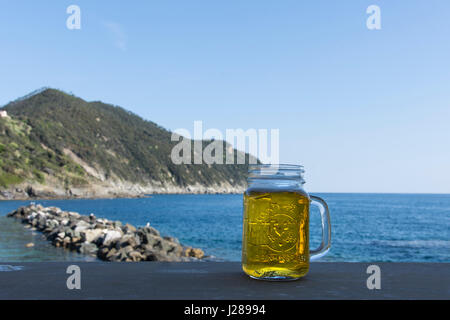 Ein Glas Bier auf dem Tisch im Freien direkt am Meer Stockfoto