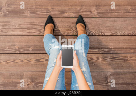 Modische Frau mit Smart Phone und Holzboden Stockfoto