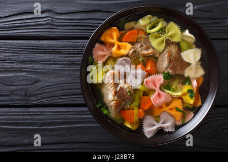 Köstliche Suppe mit Fleisch, bunten Farfalle Nudeln und Gemüse in eine Schüssel Nahaufnahme. Horizontale Ansicht von oben Stockfoto
