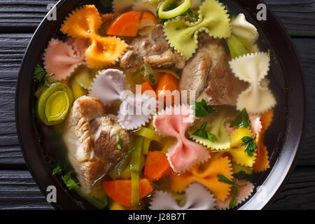Deftige Fleischsuppe mit farbigen Farfalle Nudeln und Gemüse in eine Schüssel Nahaufnahme. horizontale Ansicht von oben Stockfoto