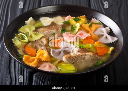 Deftige Fleischsuppe mit farbigen Farfalle Nudeln und Gemüse in eine Schüssel Nahaufnahme. horizontale Stockfoto