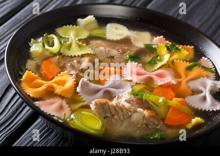 Italienische Suppe mit Schweinefleisch, farbige Farfalle Nudeln und Gemüse in eine Schüssel Nahaufnahme. horizontale Stockfoto