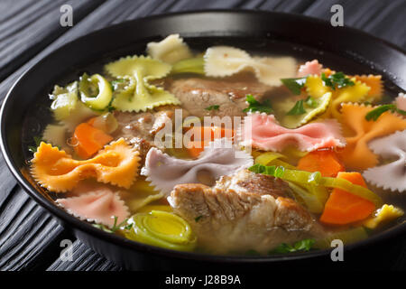 Köstliche Suppe mit Fleisch, bunten Farfalle Nudeln und Gemüse in eine Schüssel Nahaufnahme. horizontale Stockfoto