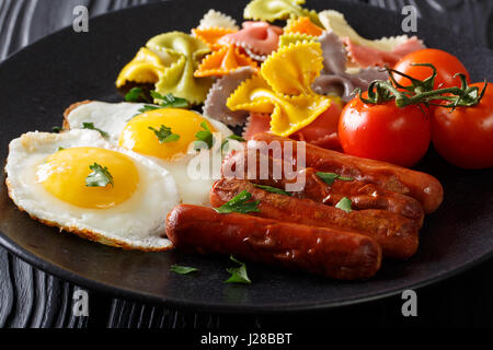 Hausgemachtes Frühstück: gebratenen Eiern, Würstchen, farbige Farfalle Pasta und Tomaten Nahaufnahme auf einer Platte. horizontale Stockfoto
