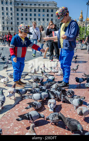 Junge Brüder stehen und füttern von Tauben in der Plaça de Catalunya im Zentrum von Barcelona. Stockfoto