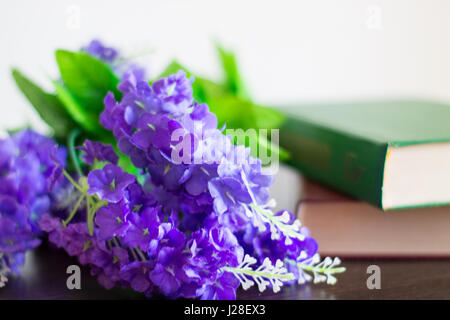 Bücher mit lila Blüten auf einem Holztisch. Stockfoto
